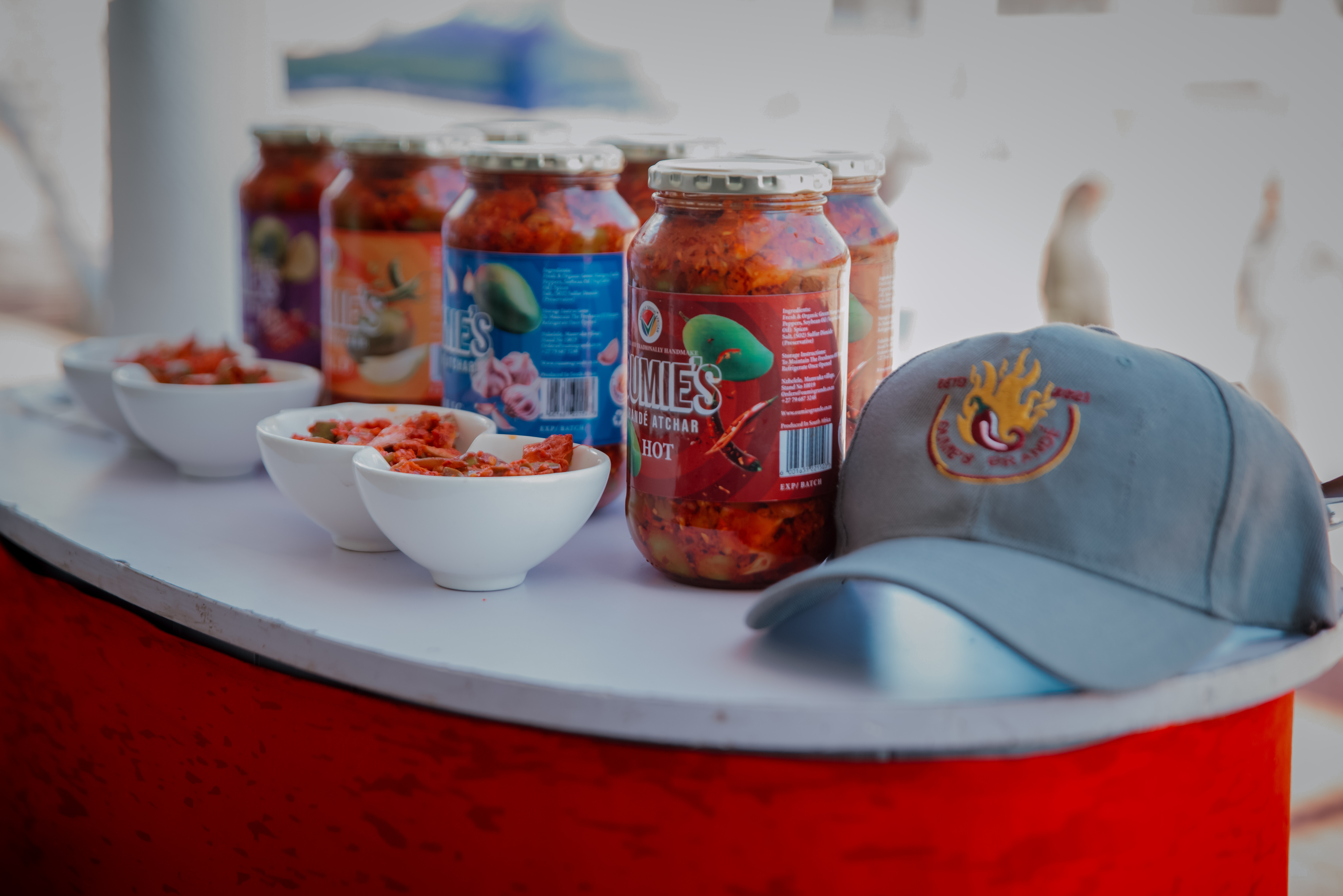 Jars of tomato based good with a hat on the side